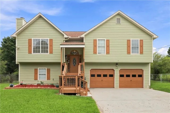 Split-level residence featuring vinyl siding, a covered entry porch, and a two-car garage