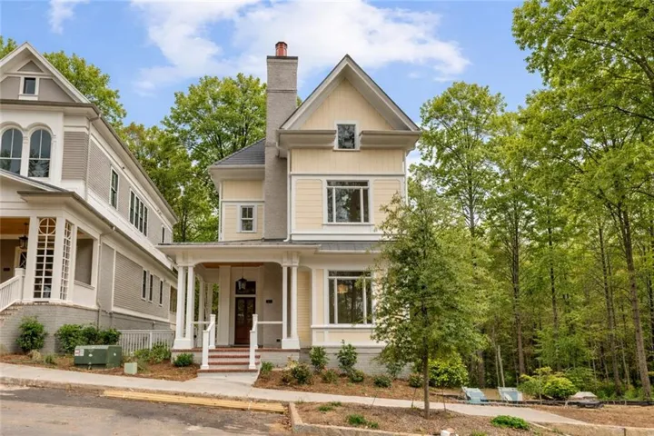 View of front facade with covered porch, a chimney, and board and batten siding