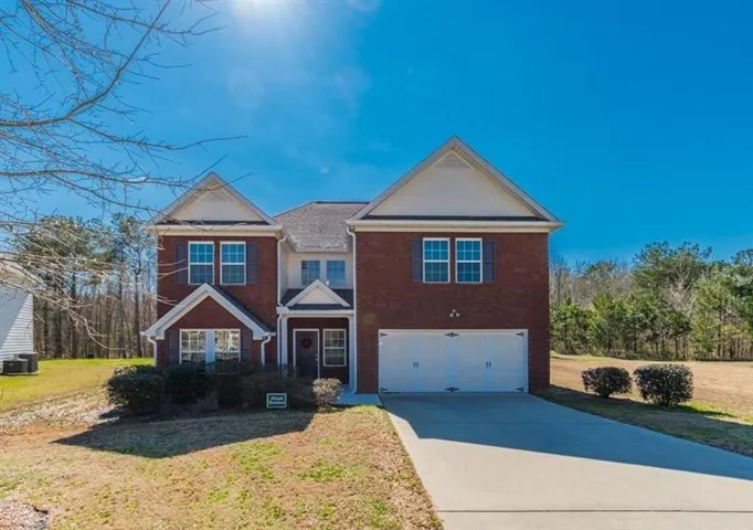 View of front of property featuring concrete driveway, an attached garage, a front lawn, and brick siding