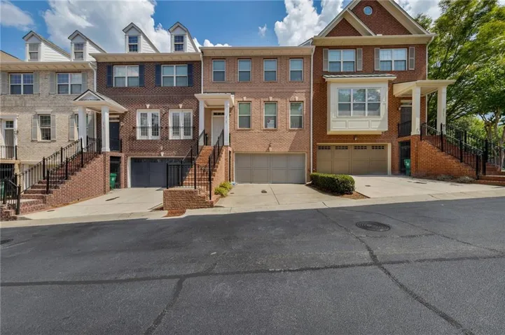 Brick-clad townhome with prominent gable roofline, multiple dormer windows, and a two-car garage