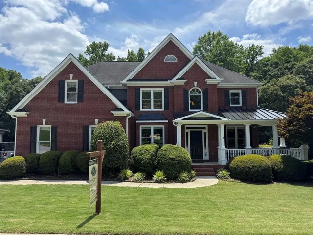 Traditional brick exterior with white trim, covered front porch, and manicured landscaping