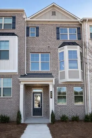 Multi-story townhouse exterior featuring a gray brick facade with white trim