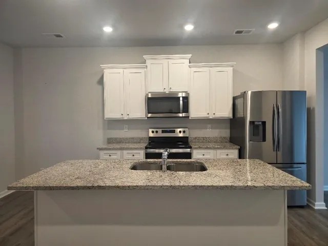 Kitchen featuring white cabinetry, light-toned countertops, stainless steel appliances, and recessed lighting