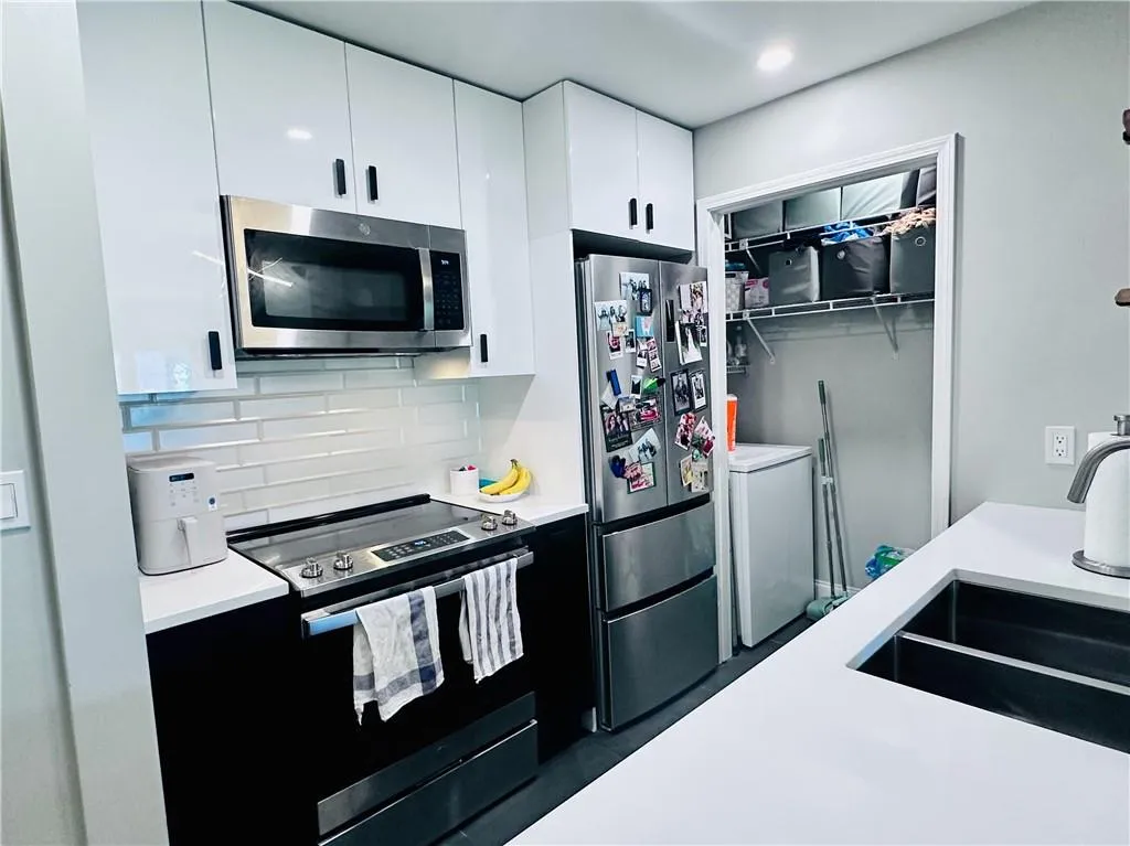 Kitchen with stainless steel appliances, white cabinetry, backsplash, modern cabinets, and washer / dryer