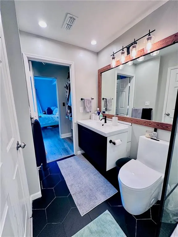 Full bath with vanity,  tile, recessed lighting & view of closet through to bedroom