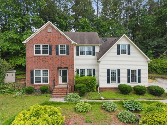 Two-story residence featuring a brick facade and white siding accents