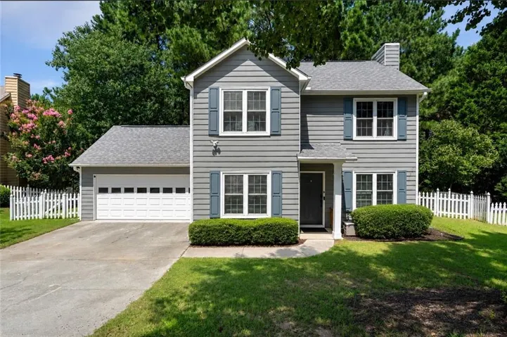 Two-story residence featuring horizontal siding, a single-car garage, and white picket fencing
