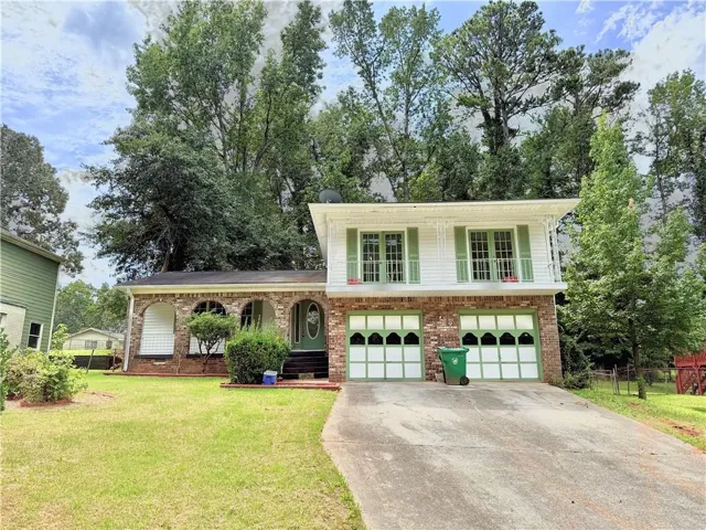 Split level home with concrete driveway, brick siding, an attached garage, and a porch