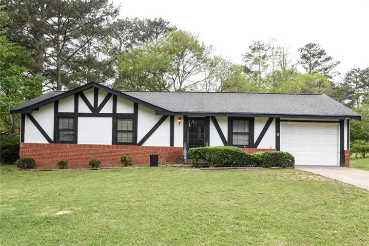 View of front facade featuring brick siding, a front lawn, and stucco siding