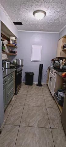 Galley kitchen featuring tile flooring, built-in cabinetry with storage shelving, stainless steel appliances including range and refrigerator, and recessed ceiling lighting
