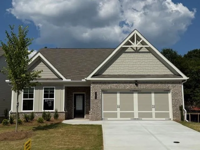 Front exterior featuring a brick and siding facade, a double-car garage with carriage-style doors, a concrete driveway, and a covered entry