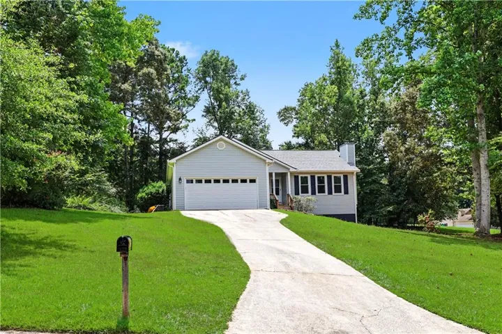 Single-story property with light-colored siding, a prominent two-car garage, and a concrete driveway