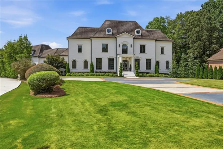 Stately white brick exterior with a multi-gabled roof, arched entryway, and circular driveway