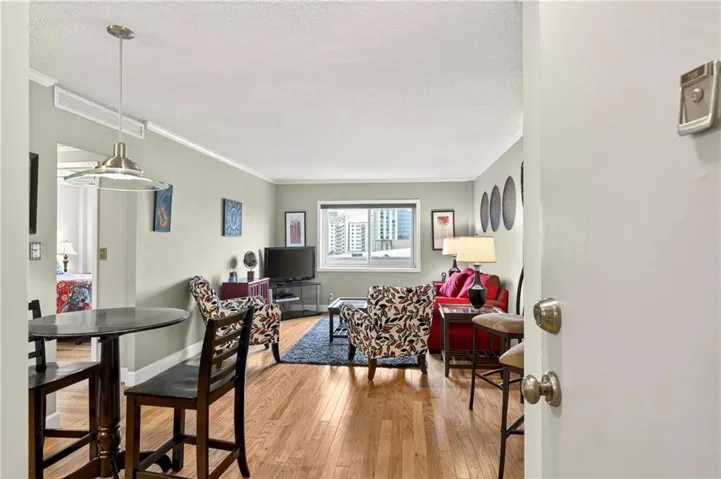 Dining space with light wood-style floors, crown molding, and a textured ceiling