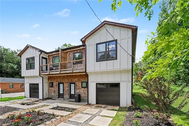 Modern duplex exterior featuring board-and-batten siding, natural wood shingles, dark frame windows, and individual garage doors