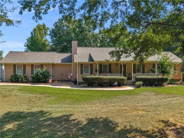 Single-story residence featuring a covered front porch, light-colored siding, dark shutters, and a prominent chimney