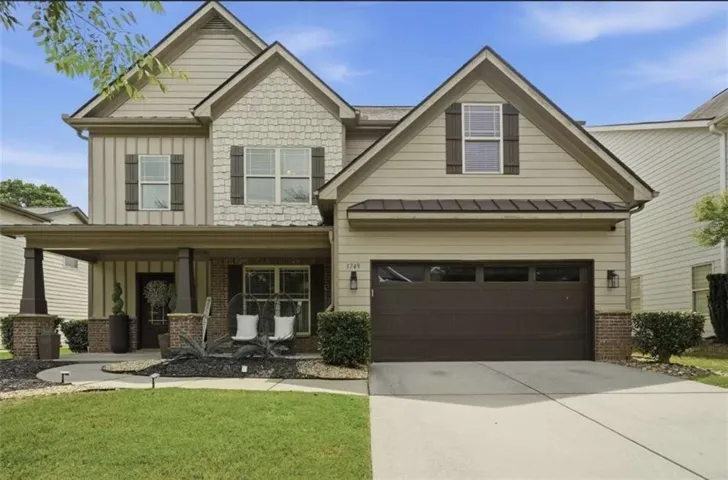 Two-story residence featuring a covered front porch, a two-car garage with a panel door, and gabled rooflines