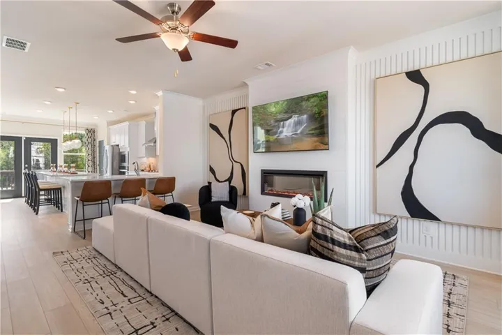 Recessed lighting, wood-finish flooring, ceiling fan, built-in linear fireplace, and kitchen island with seating