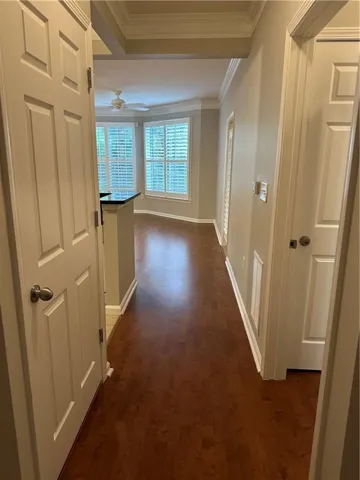 Hallway with ornamental molding and dark wood-style floors