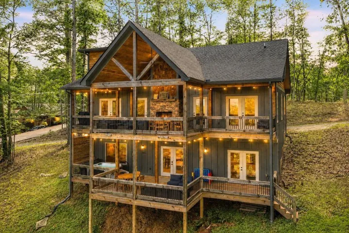 Multi-level exterior featuring stacked balconies, board and batten siding, and a prominent stone fireplace