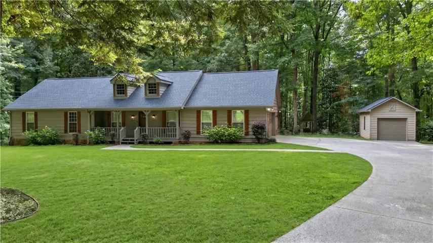 Ranch-style residence featuring a covered front porch with white railings, dormer windows, and a detached two-car garage