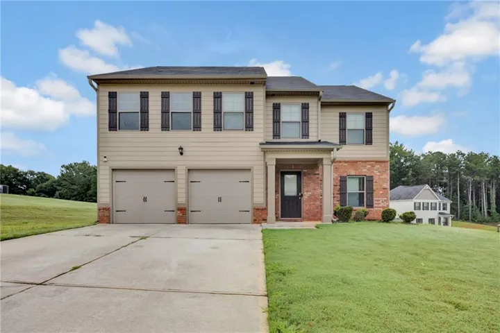 Two-story residence featuring a two-car garage, brick accents, and a covered front entry