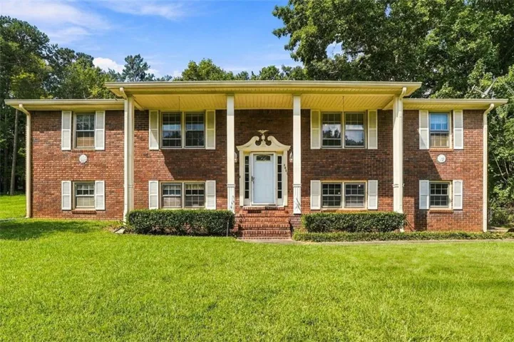 Brick exterior with white shutters, a covered entry, and a prominent front door