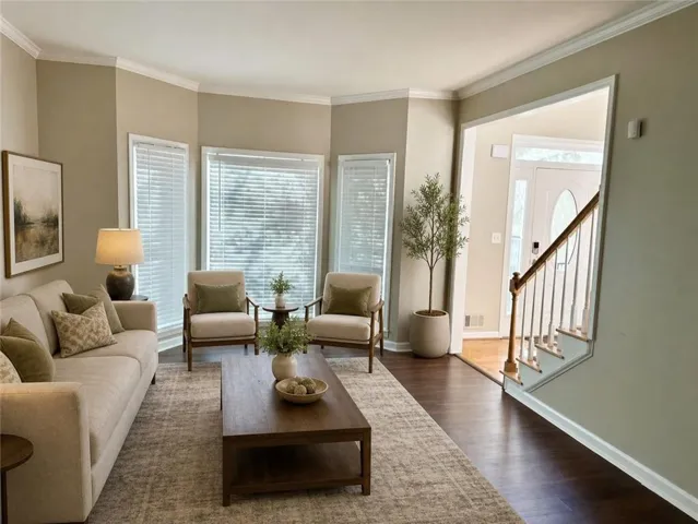 Living area featuring dark wood-finish flooring and light-toned walls with crown molding