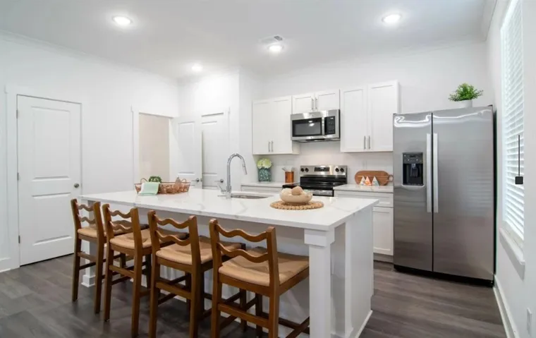 Kitchen featuring stainless steel appliances, ornamental molding, white cabinetry, a breakfast bar, and dark wood-style floors