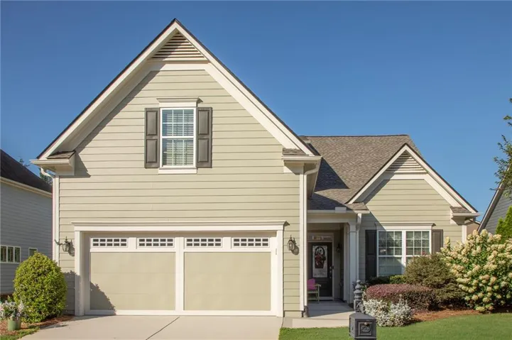 Light green siding exterior with a two-car garage featuring decorative window panels