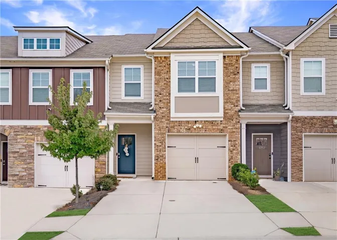 Craftsman-style home with concrete driveway, a shingled roof, and stone siding