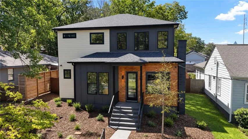 Contemporary exterior featuring multi-toned siding, black-framed windows, a wood-paneled accent wall, and a dark shingle roof