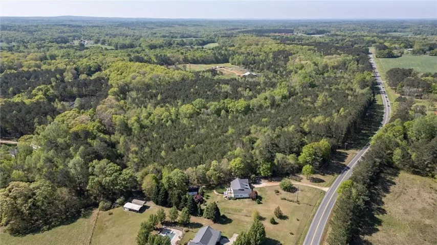 Aerial view of property and surrounding area featuring a heavily wooded area
