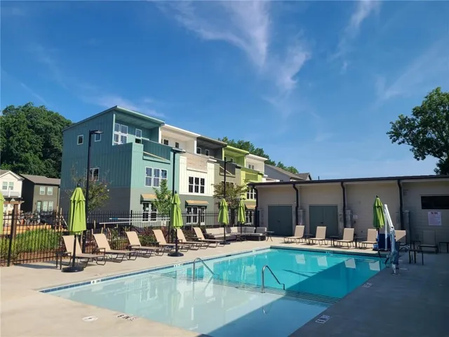 Outdoor swimming pool with concrete decking, surrounded by lounge chairs and umbrellas