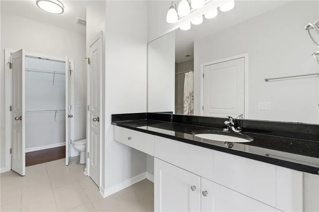 Full bathroom with a shower with shower curtain, vanity, a spacious closet, and light tile patterned floors