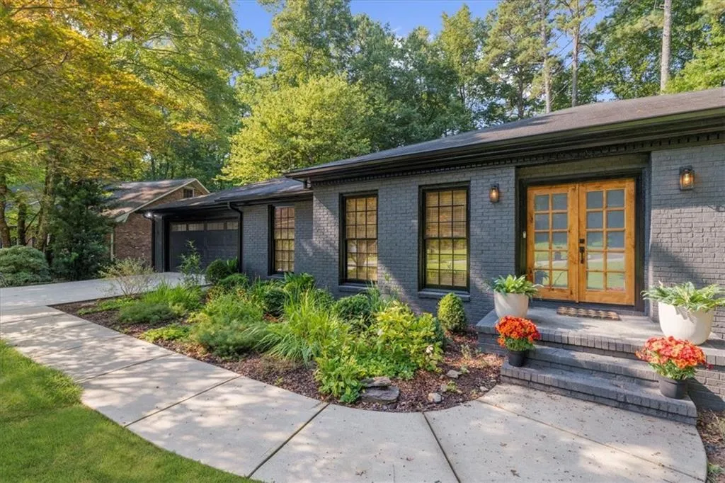 View of front of property with brick siding, a garage, french doors, and driveway