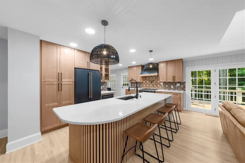 Kitchen featuring backsplash, light wood-style flooring, glass insert cabinets, a kitchen bar, and high quality fridge