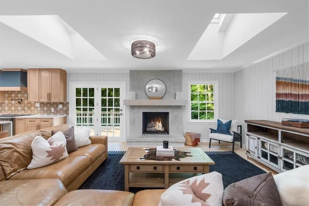 Living area featuring a skylight, a fireplace, crown molding, wood finished floors, and wood walls