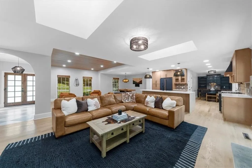 Living area featuring light wood-type flooring, a skylight, french doors, and recessed lighting