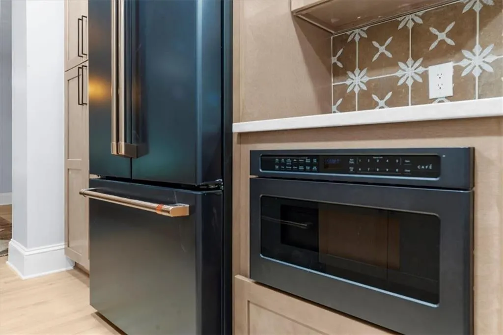 Kitchen with high end refrigerator, light wood-type flooring, and wall oven