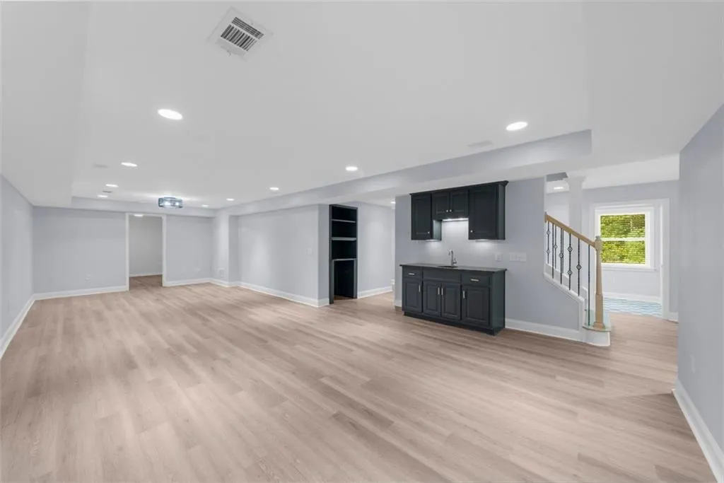 Unfurnished living room with stairs, light wood finished floors, wet bar, and recessed lighting