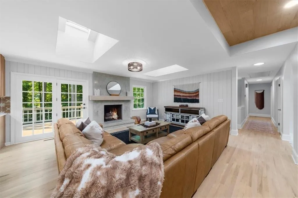 Living room featuring a skylight, light wood-type flooring, wooden walls, and a fireplace