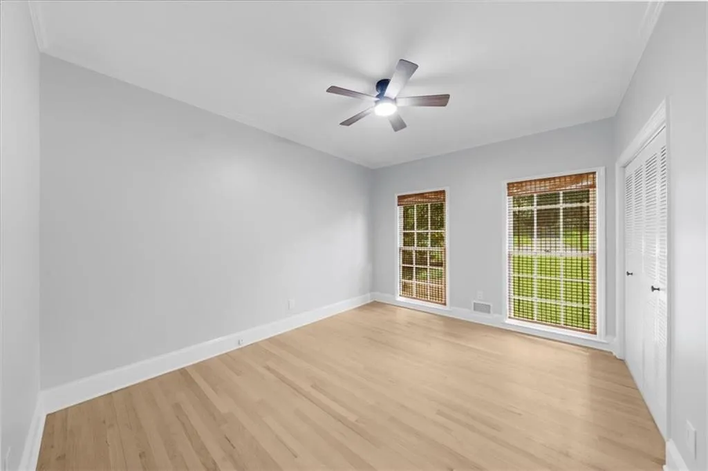 Spare room with light wood-style flooring, ornamental molding, and ceiling fan