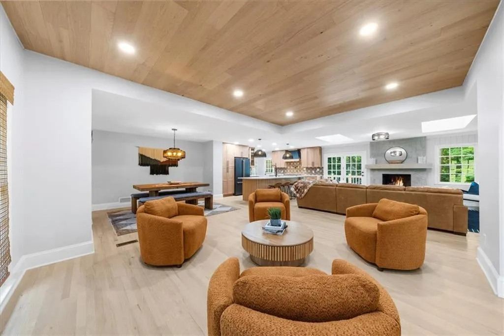 Living room featuring wooden ceiling, recessed lighting, a high end fireplace, light wood finished floors, and a skylight