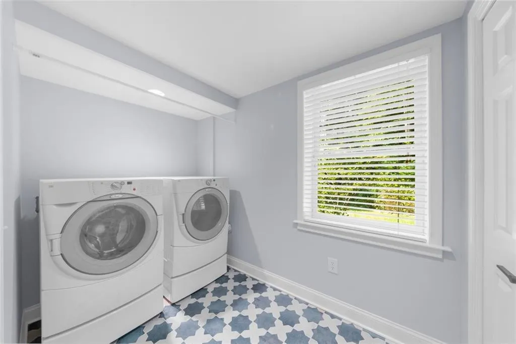 Laundry room with washer and clothes dryer and tile patterned floors