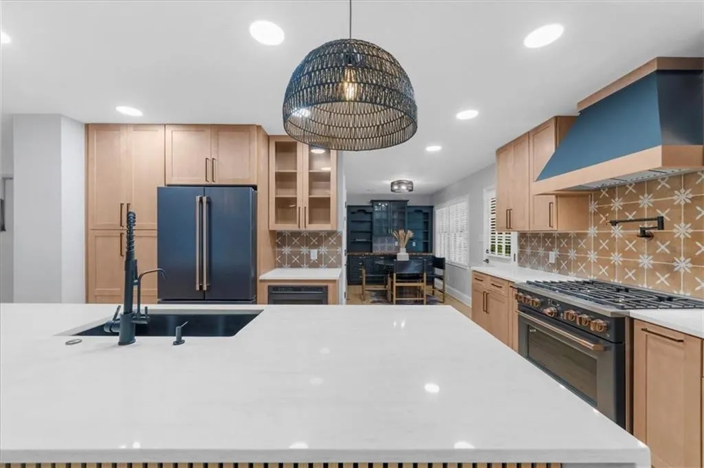Kitchen featuring glass insert cabinets, high end appliances, backsplash, custom exhaust hood, and light stone counters