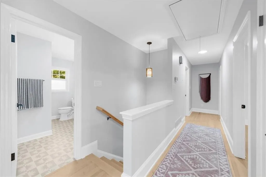 Corridor featuring attic access, an upstairs landing, and light floors