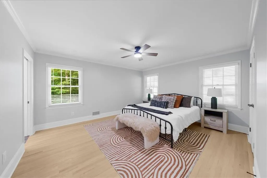 Bedroom with ornamental molding, light wood-type flooring, and ceiling fan