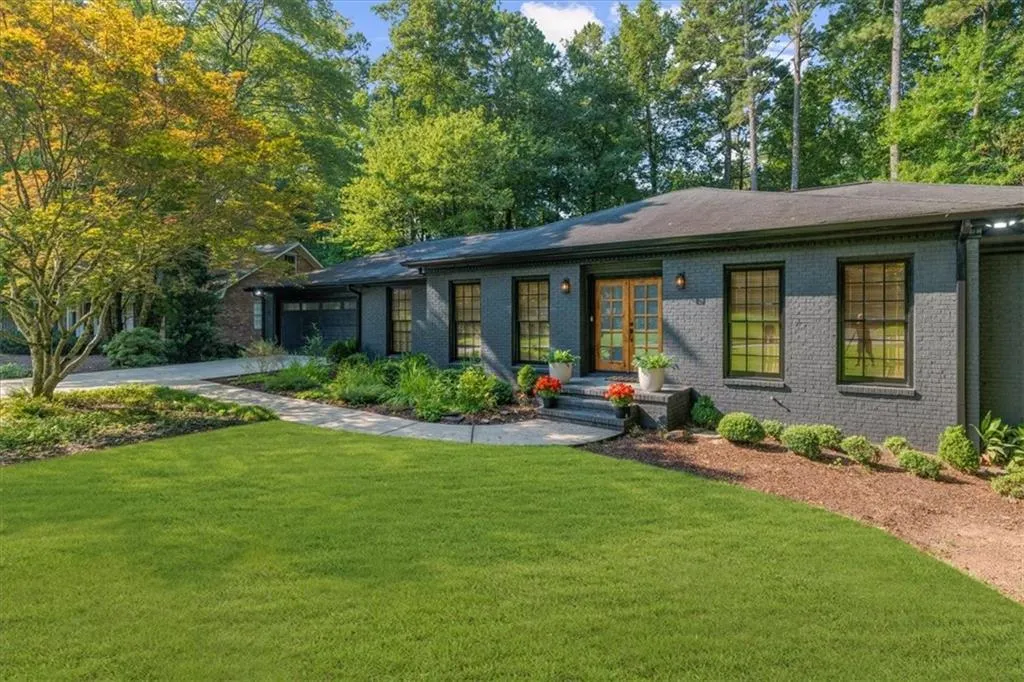 View of front of property featuring brick siding, a front lawn, a garage, and driveway