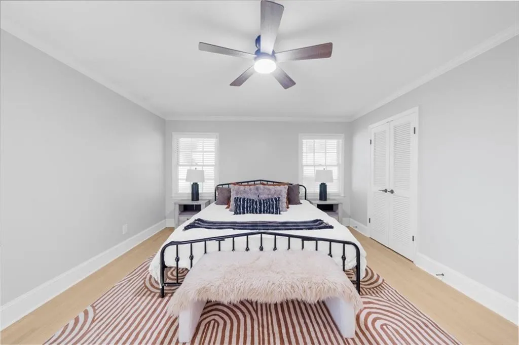 Bedroom featuring ornamental molding, light wood-type flooring, a closet, and a ceiling fan